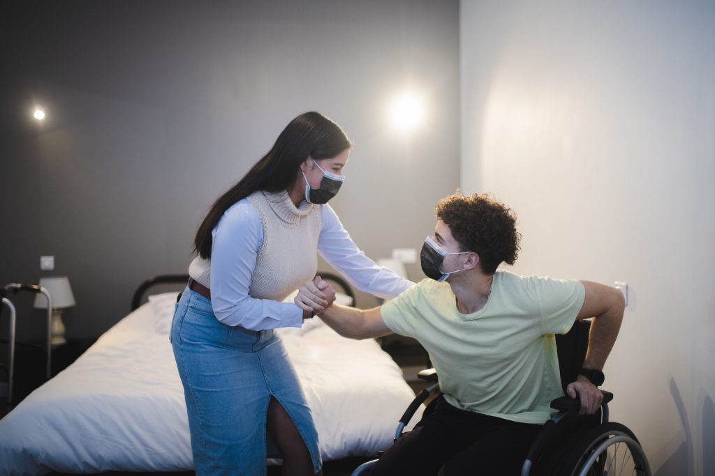 Une personne aide un jeune homme en fauteuil roulant